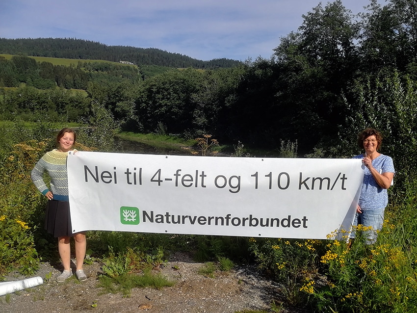 To aktivister holder et banner mot motorveiutbygging