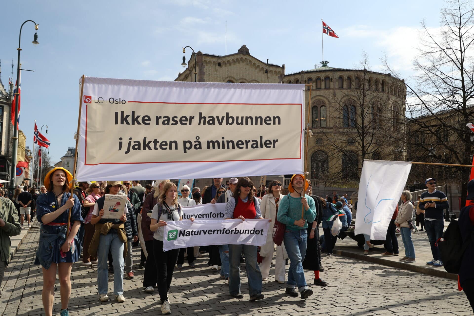 Mennesker går i 1.mai-tog og holder oppe parolen "Ikke raser havbunnen i jakten på mineraler" foran Stortinget.