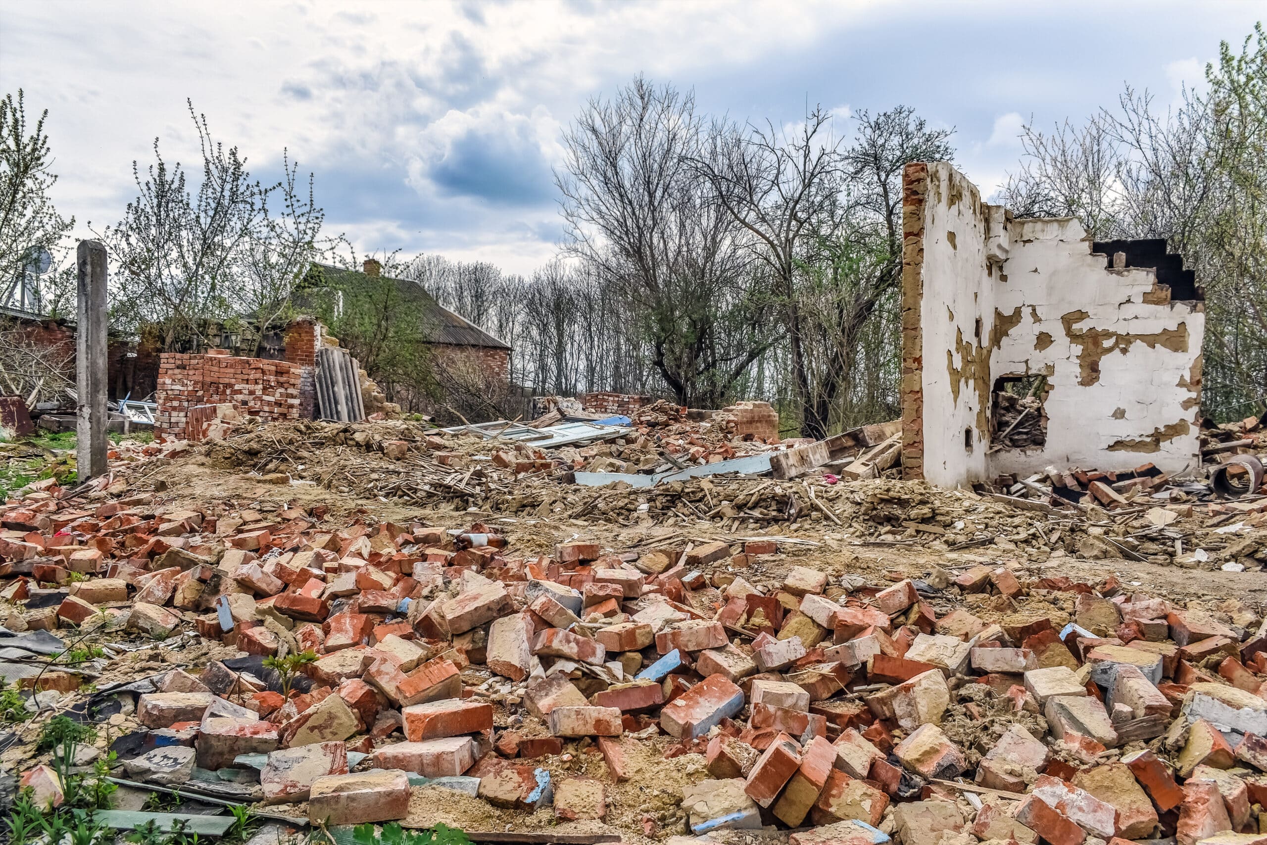 Ruiner etter et landlig hus i Ukraina. Planker, skifer, murstein, gips og annet konstruksjonsavfall ligger på bakken. Bare én vegg står igjen etter det som en gang var et hjem. Foto: ioanna_alexa / Istockphoto