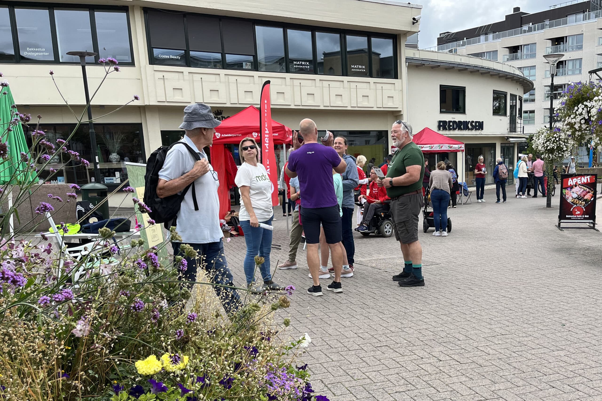 folk i gate snakker med politikere på stand