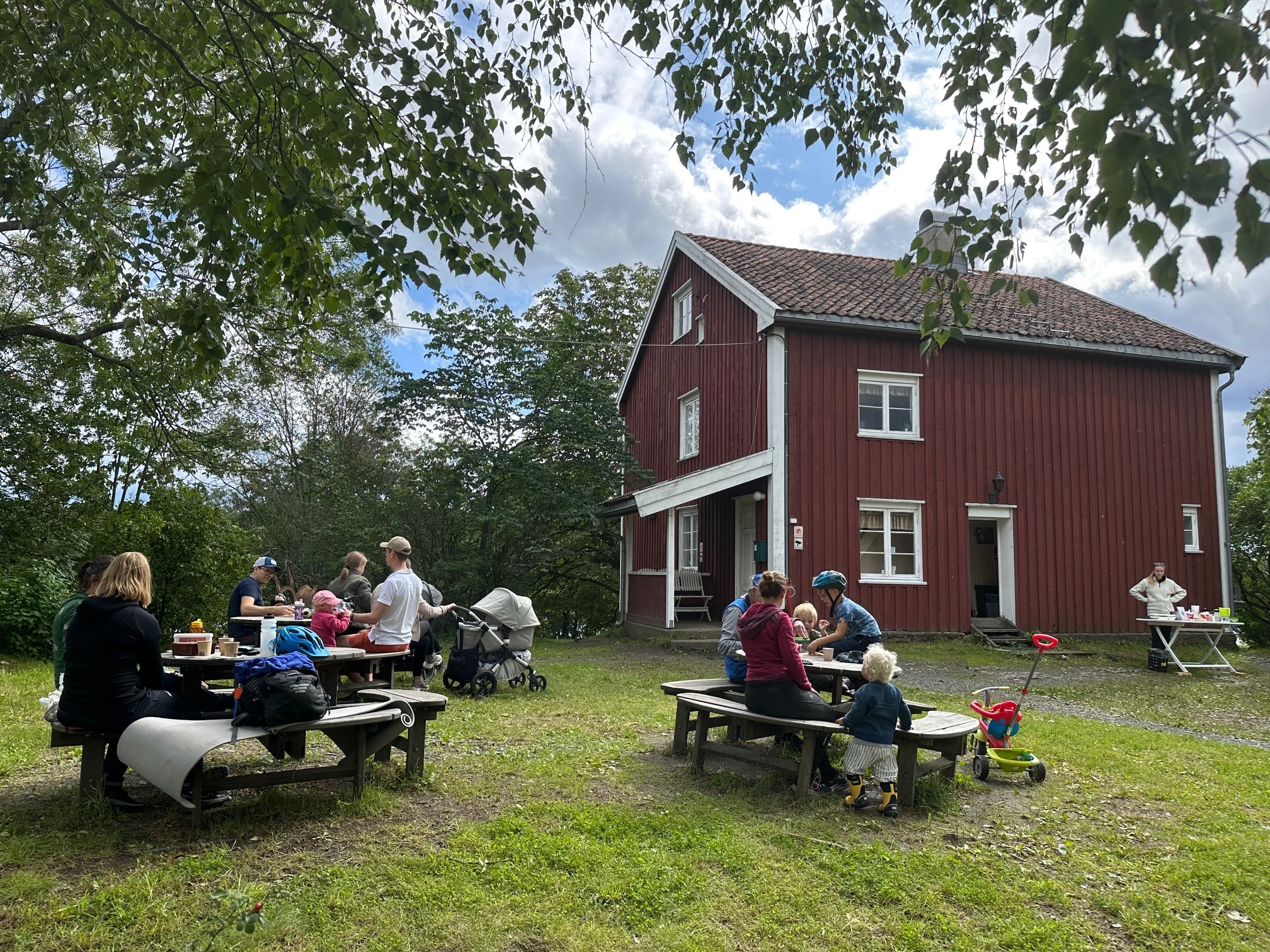 gammelt hus og tun med mennesker på benker